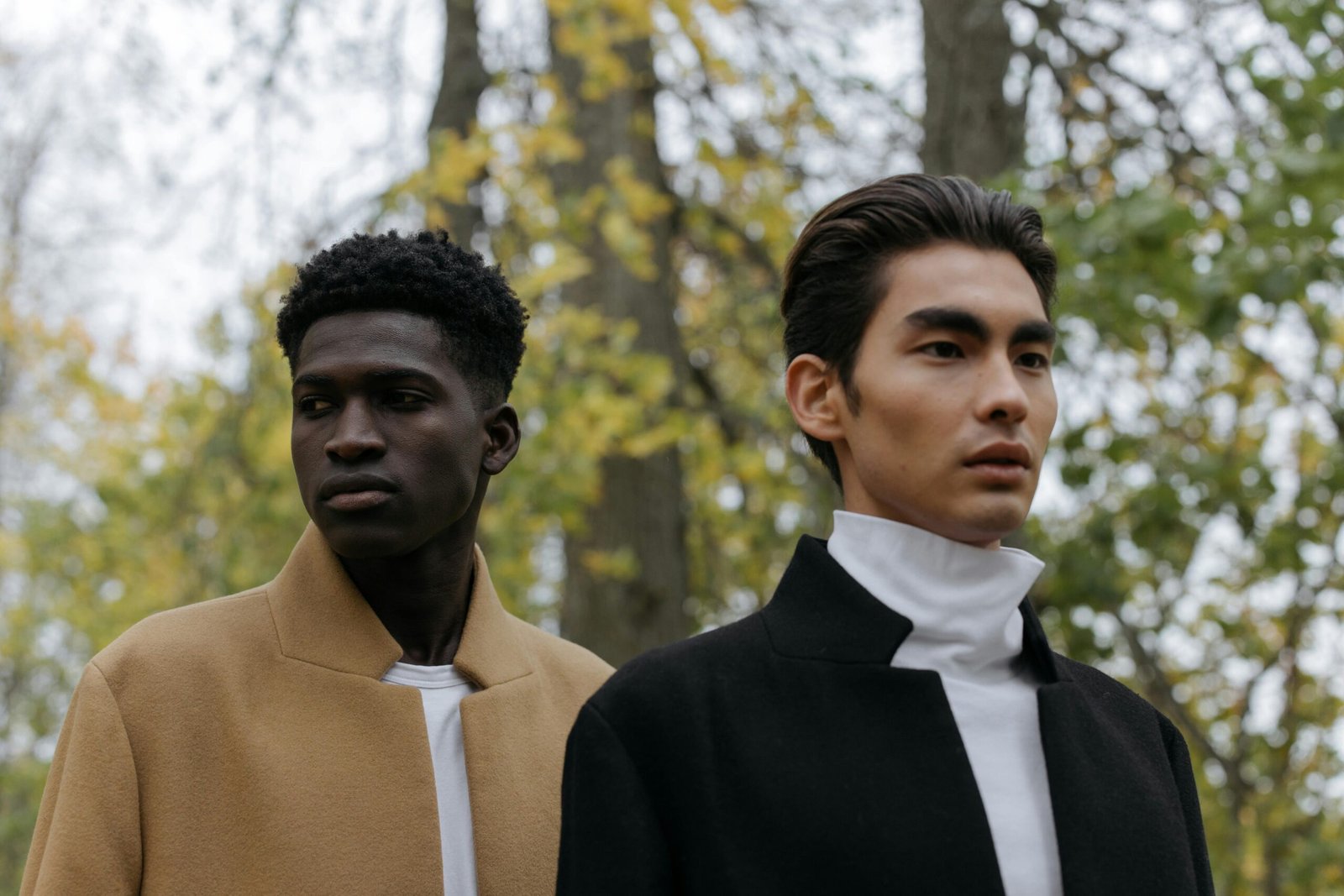 Two stylish men outdoors in autumn, showcasing elegant fashion trends.